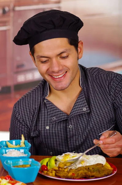 Sonriente hombre guapo en cocina comiendo un churrasco, cocina ecuatoriana —  Fotos de Stock