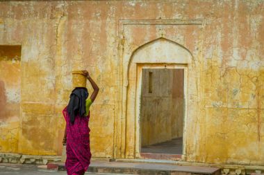 Amber, Hindistan - 19 Eylül 2017: Amber, Hindistan, sokakların bulanık bir sarı Amber Fort şehirde içinde yürüyor iken onun kafasına bir sepet taşıyan bir kadının yakın çekim