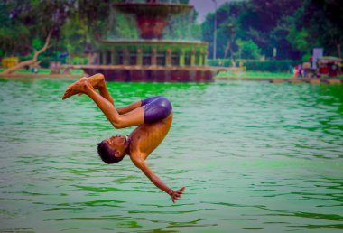 Delhi, Hindistan - 16 Eylül 2017: tanımlanamayan Hintli çocuk bir backflip Delhi, Hindistan bir havuzda su, yeşil suda yapıyor