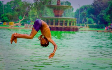 Delhi, Hindistan - 16 Eylül 2017: tanımlanamayan Hintli çocuk bir backflip Delhi, Hindistan bir havuzda su, yeşil suda yapıyor