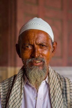 Delhi, Hindistan - 27 Eylül 2017: Kamera arka plan bulanık Jama Mescidi Camii Delhi, Hindistan tapınakta içinde bakarak beyaz sakalı ile beyaz bir Hint şapka giyen bir adam portresi