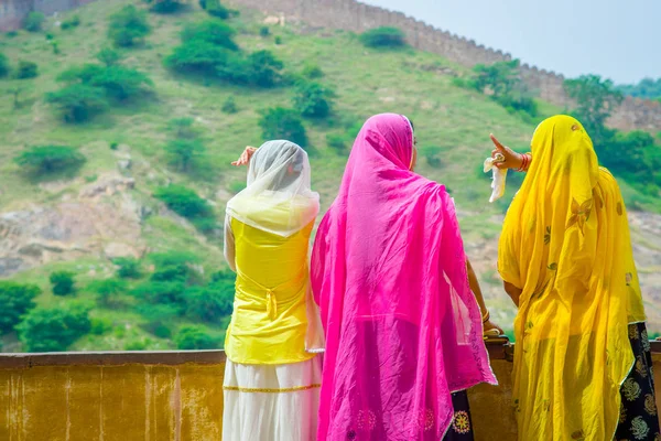 Amer, India - 19 de septiembre de 2017: Mujeres no identificadas posando en una pared empedrada, vistiendo una ropa amarilla y rosa, y disfrutando de la vista del lago Maota en Amber Fort en Jaipur, Rajastán, India —  Fotos de Stock