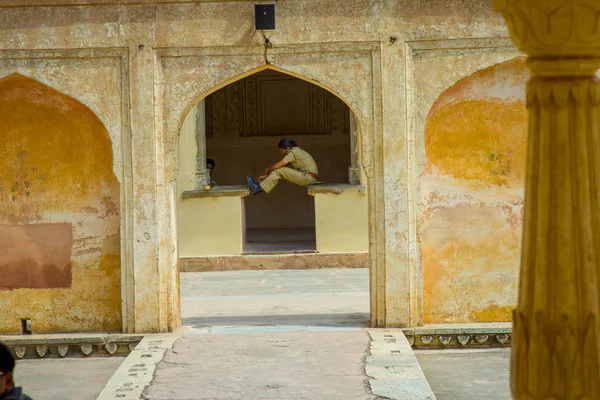 Amber, Índia - 19 de setembro de 2017: Mulher não identificada vestindo um uniforme, sentada e flexionando as pernas em uma estrutura apedrejada no palácio localizado em Rajastão, Índia — Fotografia de Stock