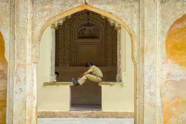 Ambra, India - 19 settembre 2017: Donna non identificata che indossa un'uniforme, seduta e flettente le gambe in una struttura lapidata nel palazzo situato nel Rajasthan, India — Foto Stock
