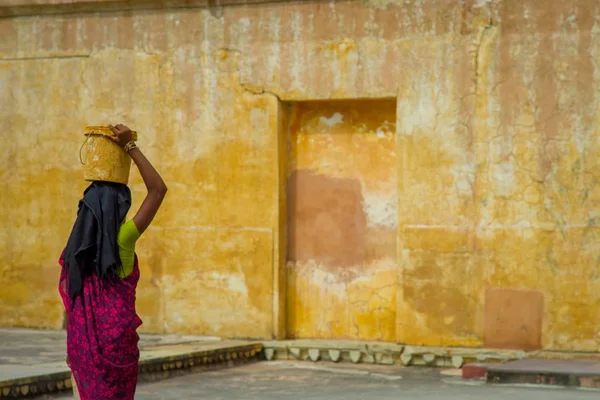Amber, Inde - Le 19 septembre 2017 : Gros plan d'une femme portant dans sa tête un panier alors qu'elle se promène à l'intérieur de la ville dans le fort Amber dans les rues d'Amber, en Inde, dans un jaune flou — Photo