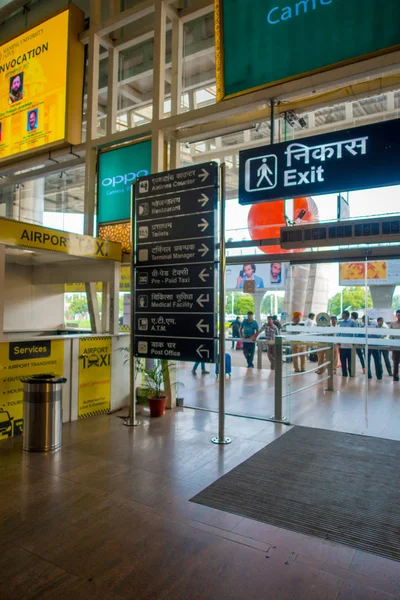 DELHI, INDIA - 19 SETTEMBRE 2017: Segnale informativo all'uscita dell'aeroporto internazionale di Delhi e folla, l'aeroporto internazionale Indira Gandhi è il 32esimo più trafficato del mondo — Foto Stock