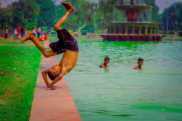 델리, 인도-9 월 16 일, 2017: 미확인된 그룹 인도 소년 smming와 델리, 인도에 연못에 있는 물, 녹색 물에서 공중 제비를 하 고 단일 소년의 — 스톡 사진