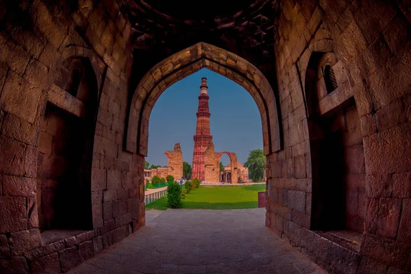 DELHI, ÍNDIA - SETEMBRO 25 2017: Bela vista de Qutub Minar, através de um arco apedrejado, um dos patrimônios mundiais da UNESCO, construído no início do século XIII, localizado no sul de Delhi, Índia — Fotografia de Stock