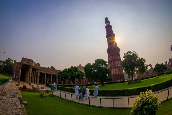 DELHI, ÍNDIA - SETEMBRO 25 2017: Pessoas não identificadas andando perto de Qutub Minar ao pôr do sol, a torre de pedra mais alta do mundo, e o minarete mais alto da Índia, construído com — Fotografia de Stock