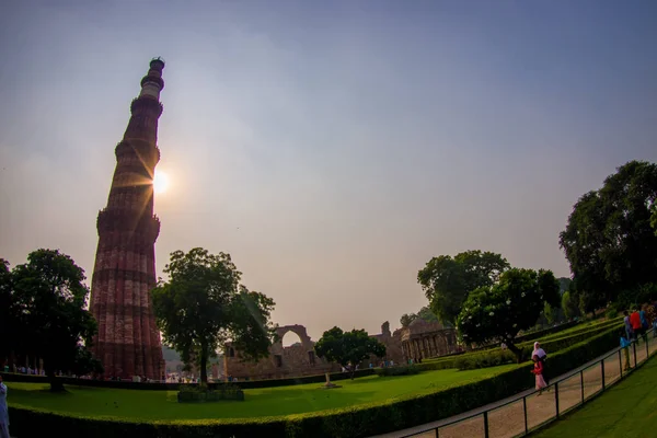 DELHI, ÍNDIA - SETEMBRO 25 2017: Pessoas não identificadas andando perto de Qutub Minar ao pôr do sol, a torre de pedra mais alta do mundo, e o minarete mais alto da Índia, construído com — Fotografia de Stock