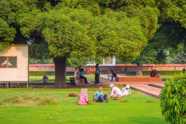 Delhi, Hindistan - 25 Eylül 2017: Park kırmızı kale, Delhi, güzel güneşli bir günde açık oturan kimliği belirsiz insanlar