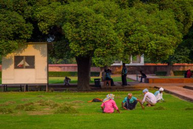 Delhi, Hindistan - 25 Eylül 2017: Park kırmızı kale, Delhi, güzel güneşli bir günde açık oturan kimliği belirsiz insanlar