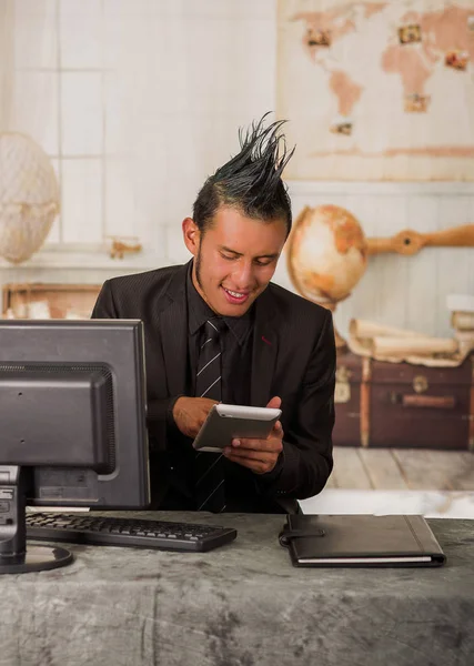 Nahaufnahme eines Büropunk-Arbeiters, der einen Anzug mit Wappen trägt und stattdessen sein Tablet benutzt, um im unscharfen Hintergrund am Computer zu arbeiten — Stockfoto
