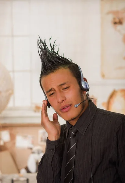 Close up of office punk man wearing a suit with a crest, wearing aheadphones in a blurred background — Stock Photo, Image