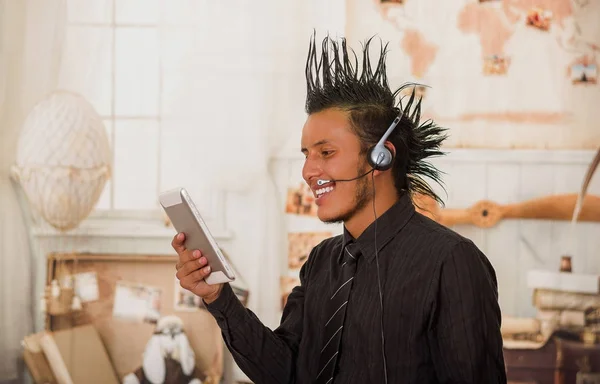 Nahaufnahme eines Büropunks, der einen Anzug mit Wappen trägt, Kopfhörer im Kopf hat und sein Tablet im Büro vor verschwommenem Hintergrund benutzt — Stockfoto