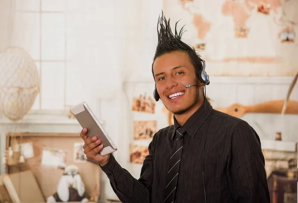 Close up of office punk man, vestindo um terno com uma crista, com fones de ouvido na cabeça e usando seu tablet no escritório em um fundo embaçado — Fotografia de Stock