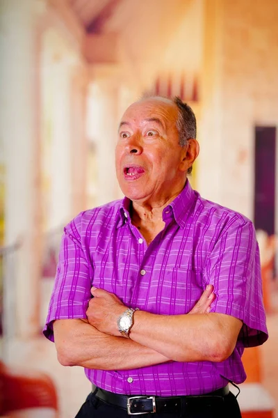 Portrét šťastný zralé muže, s rukama přešel a na sobě fialové tričko čtvercové rozostřeného pozadí — Stock fotografie