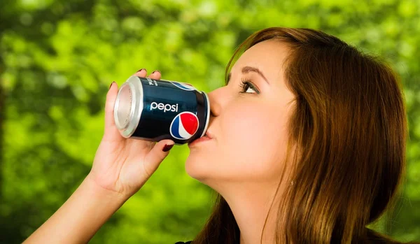 Quito, Ecuador 06 maggio 2017: Ritratto di una bella giovane donna che beve un pepsi su sfondo verde sfocato — Foto Stock