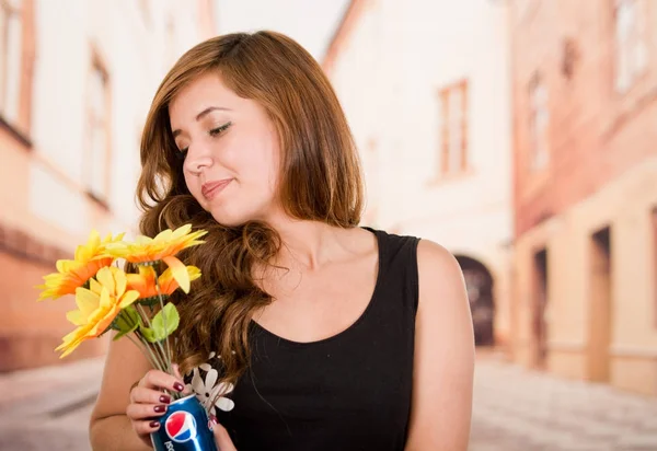 Quito, Ecuador May, 06, 2017: Pretty young woman holding a pepsi with sunflowers inside in blurred city background — Stock Photo, Image