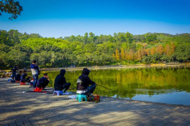 Shenzen, Çin - 29 Ocak, 2017: Lian Hua Shan içinde park, büyük rekreasyon alanı, su Gölü sorrounded Mevkii'nde ise ağaçlar, güzel mavi gökyüzü oturan insanlar,