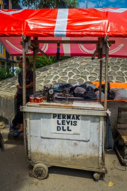 Jakarta, Endonezya - 3 Mart, 2017: onun küçük işletme vagon yanında duran, küçük onarım sunan yerel adam