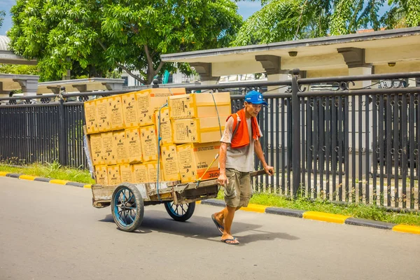 ДЖАКАРТА, ИНДОНЕЗИЯ - 3 марта 2017 года: Местный рабочий тянет тележку с картонными коробками на улице — стоковое фото