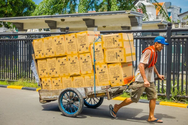 JAKARTA, INDONESIA - 3 DE MARZO DE 2017: Trabajador local tirando del carro lleno de cajas de cartón en la calle —  Fotos de Stock