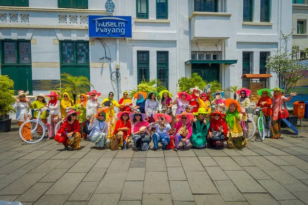 ДЖАКАРТА, ИНДОНЕЗИЯ - 3 марта 2017 года: Группа очень красочных женщин в традиционном индонезийском костюме, некоторые с велосипедами, позируют перед камерой на городской площади — стоковое фото