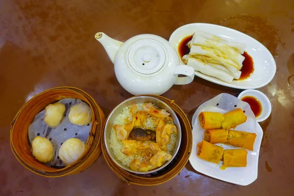 Verschiedenes chinesisches Essen, Knödel und Reisnudelrollen, berühmte Gerichte der chinesischen Küche auf einem Holztisch, Draufsicht. chinesisches Restaurantkonzept, asiatisches Bankett in Hongkong — Stockfoto