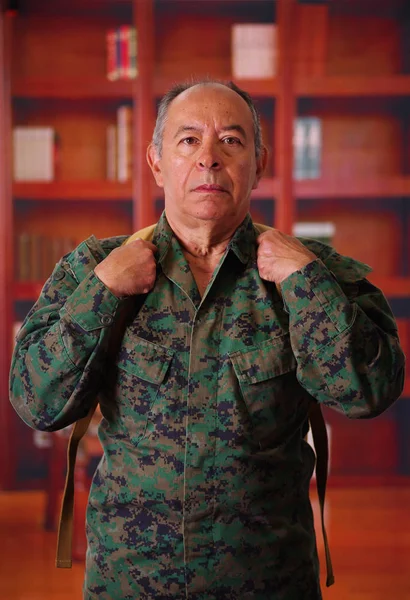 Close up de um soldado veterano sério vestindo um uniforme militar e uma mochila, em um fundo turvo — Fotografia de Stock