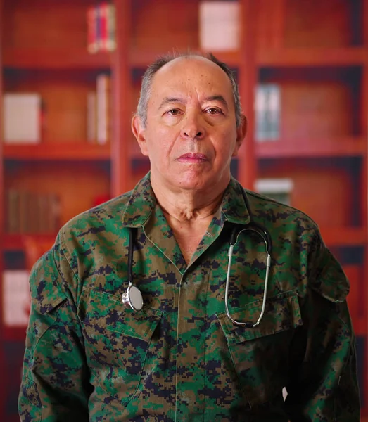 Primer plano de un soldado veterano serio que llevaba un uniforme militar, con un estetoscopio alrededor de su cuello, en un fondo borroso — Foto de Stock