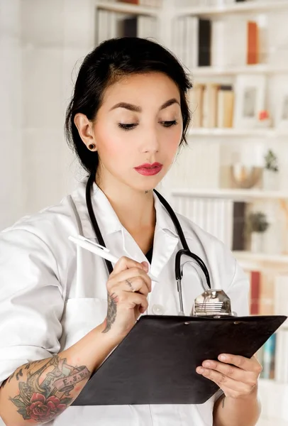 Mooie getatoeëerd jonge dokter in office achtergrond — Stockfoto