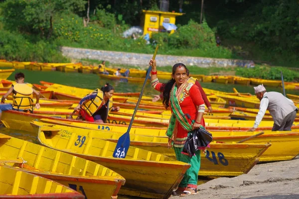 Pokhara, Nepal - 04 November 2017: Onbekende vrouw met in haar hand een peddel met sommige gele boten in het Begnas meer in Pokhara, Nepal — Stockfoto