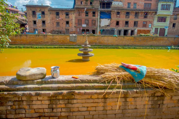 BHAKTAPUR, NEPAL - NOVEMBRO 04, 2017: Fechar a cena urbana tradicional com uma lagoa artificial de água amarela na cidade de Bhaktapur, Nepal — Fotografia de Stock