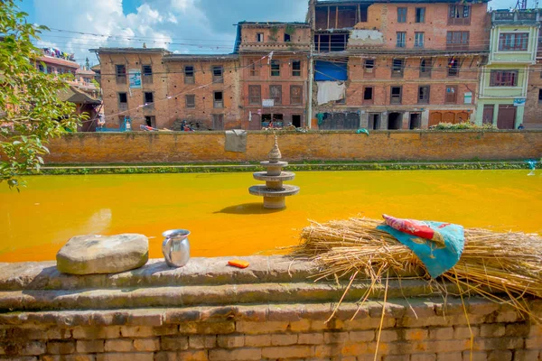 BHAKTAPUR, NEPAL - NOVEMBRO 04, 2017: Fechar a cena urbana tradicional com uma lagoa artificial de água amarela na cidade de Bhaktapur, Nepal — Fotografia de Stock