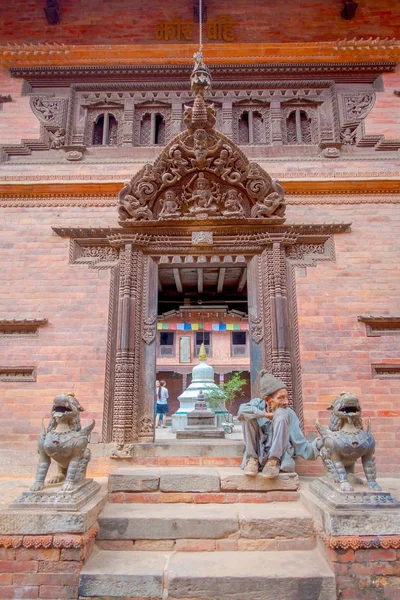 BHAKTAPUR, NEPAL - 04 DE NOVIEMBRE DE 2017: Hombre no identificado sentado en la entrada del antiguo templo hindú en la plaza Durbar en Bhaktapur, esta es la ciudad con más templos para la zona — Foto de Stock