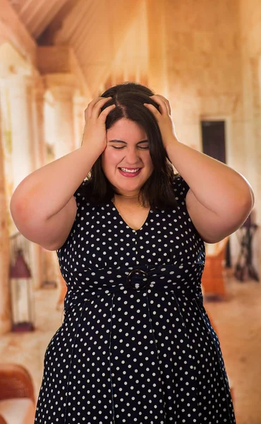 Primo piano di giovane bella plus size modello in abito nero, con entrambe le mani nella testa, xxl donna in studio sfondo sfocato — Foto Stock