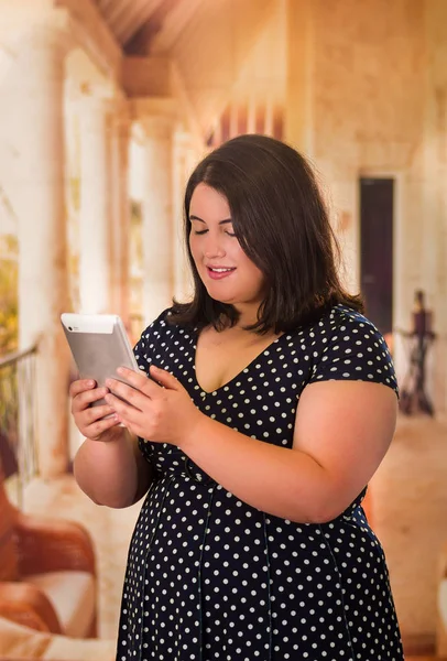 Close up of beautiful fat woman in a beautiful dress using her tablet in a blurred background — Stock Photo, Image