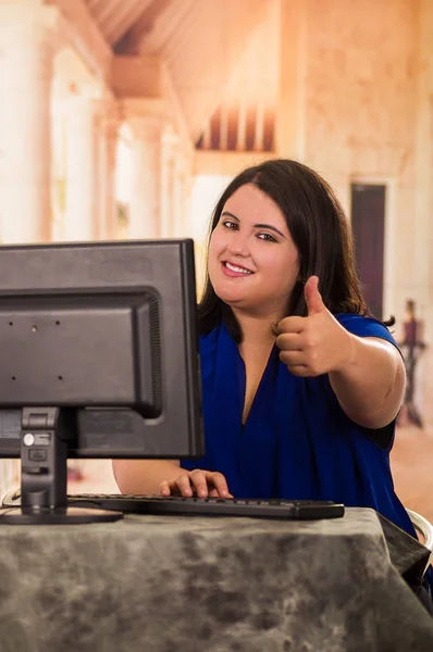 Nahaufnahme einer dicken Frau, die im Büro arbeitet, während sie mit erhobenen Daumen vor ihrem Schreibtisch sitzt — Stockfoto