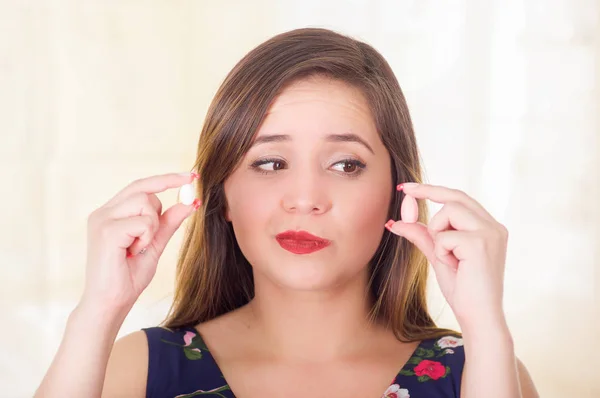 Portrait of a confused woman holding in both hands a soft gelatin vaginal tablet or suppository, treatment of diseases of the reproductive organs of women and prevention of womens health, in a — Stock Image Portrait of a confused woman holding in both hands a soft gelatin vaginal tablet or suppository, treatment of diseases of the reproductive organs of women and prevention of womens health, in a Stock Photo