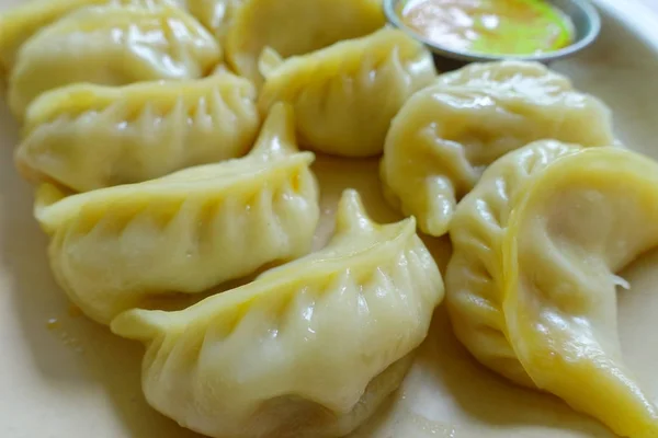 Primo piano di Momo al vapore servito in un piatto bianco. Un cibo popolare nepalese che è comune anche in Chiana, Bhutan, Tibet e India — Foto Stock