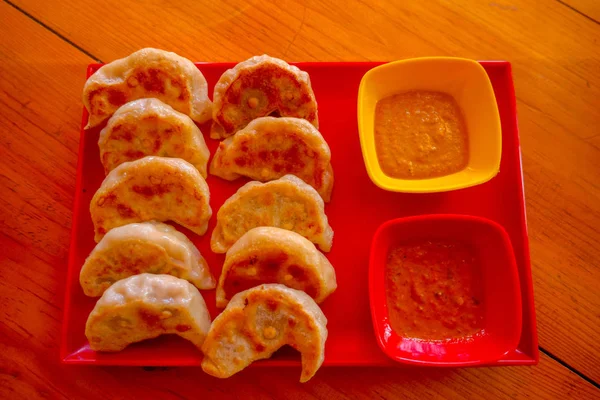 Oben Blick auf gedämpftes Essen momo, mit einer gelben und roten Schüssel mit Sauce. eine beliebte nepalesische Speise, die auch in Chiana, Bhutan, Tibet und Indien verbreitet ist, vor einem hölzernen Tischhintergrund — Stockfoto