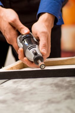 Arka plan bulanık gri bir tablo ahşap bir çerçeve içinde bir Parlatıcı kullanan bir hardworker adam closeup