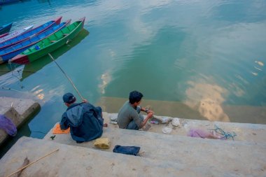 Pokhara, Nepal - 04 Eylül 2017: lakeshore içinde bazı tekneler Nepal Pokhara şehirde suda phewa göle ile Balık tutma tanımlanamayan kişi