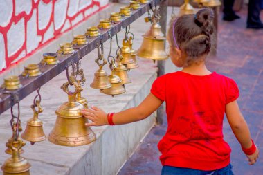 Pokhara, Nepal 10 Ekim 2017: farklı boyut Taal Barahi mandire Tapınak, Pokhara, Nepal asılı çanları dokunmadan güzel küçük bir kız