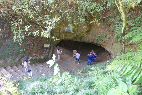 Pokhara, Nepal - 12 de setembro de 2017: Grupo não identificado de pessoas na entrada da Caverna do Morcego, com algumas vegetações cobrindo o enter, em língua nepalesa, é chamado Chameri Gufa. A caverna é feita de — Fotografia de Stock