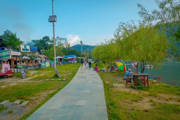 Pokhara, Nepal - 04 de septiembre de 2017: Gente no identificada huyendo en la apedreada orilla del lago con algunos camiones de comida vendiendo comida, en un hermoso día en la ciudad de Pokhara, Nepal — Foto de Stock