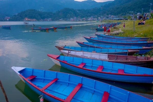 Pokhara, Nepal - 04 September 2017: Niet-geïdentificeerde mensen zitten in een oever van het meer genieten van het prachtige uitzicht op de blauwe boten in het water in de stad Pokhara, Nepal — Stockfoto