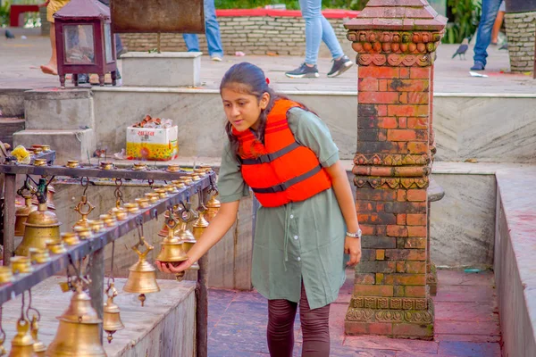 POKHARA, NEPAL 10 DE OCTUBRE DE 2017: Mujer joven no identificada tocando las campanas de diferentes tamaños colgadas en el templo Taal Barahi Mandir, Pokhara, Nepal —  Fotos de Stock