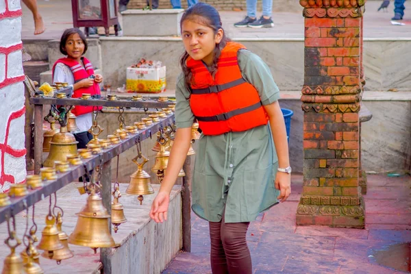 POKHARA, NEPAL 10 DE OCTUBRE DE 2017: Mujer joven no identificada tocando las campanas de diferentes tamaños colgadas en el templo Taal Barahi Mandir, Pokhara, Nepal —  Fotos de Stock